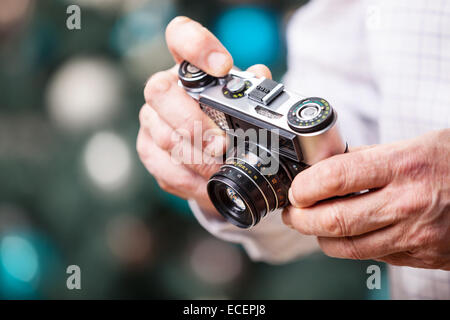 Cropped view of man holding retro camera against Christmas background Stock Photo