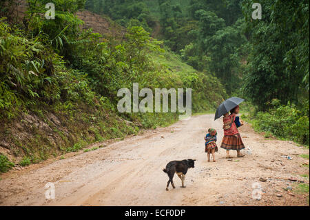 Hmong woman and her children walking along a road Stock Photo