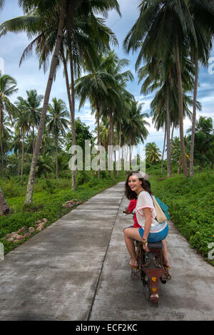 Woman riding a motorcycle taxi on a rural road in the Philippines Stock Photo