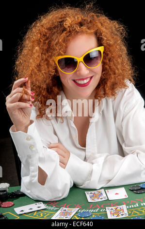 young woman croupier at the green table, while dealing the cards Stock Photo