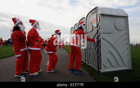 Female Santas queue for the portable toilets as hundreds take part in the annual Santa dash on Hove seafront Brighton UK 2014 Stock Photo