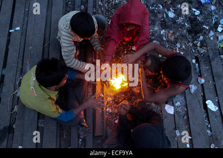 Dhaka, Bangladesh. 13th December, 2014. Homeless children create fire by using discarded wood or plastic to provide some warmth as winter temperatures drop in Dhaka. Credit:  zakir hossain chowdhury zakir/Alamy Live News Stock Photo