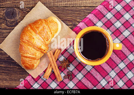 Coffee cup with a croissant on wooden table covert tablecloth. Top view Stock Photo