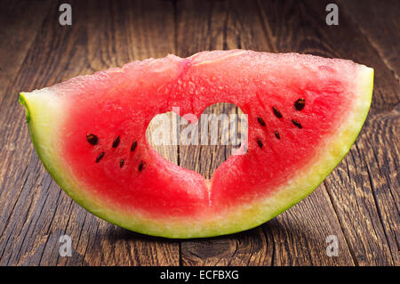 Watermelon slice with cut in the shape of heart on wooden table Stock Photo