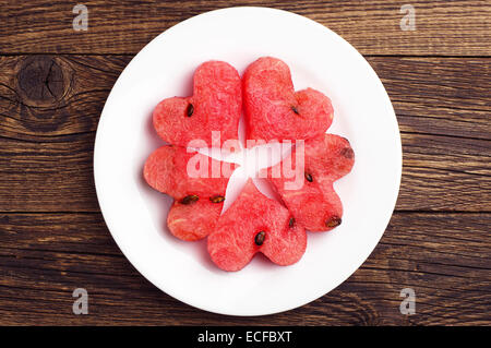 Slices of watermelon in the heart shape on vintage wooden table. Top view Stock Photo