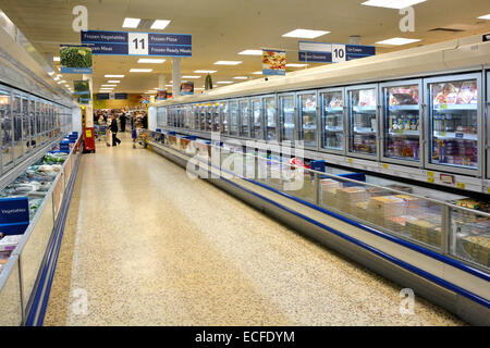 Shoppers & interior view Tesco supermarket frozen food aisle and cold cabinets shopping inside with terrazzo floor interior East London England UK Stock Photo