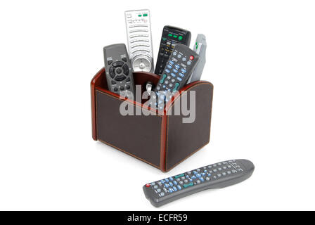 Small leather box containing many varied remote control devices used for home entertainment equipment, isolated on white. Stock Photo