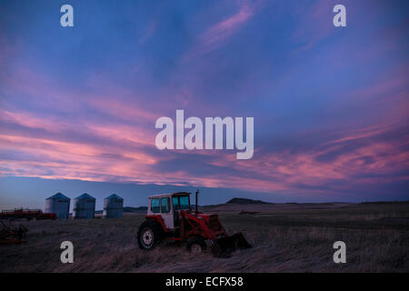 Farm equipment on the Southern Alberta prairies near Cowley at dusk.  A storm approaches over the Livingstone Range to the west. Stock Photo