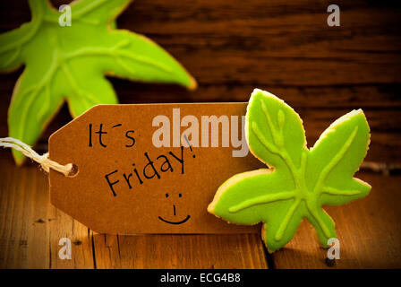 Brown Organic Label With English Text Its Friday On Wooden Background With Two Leaf Cookies And Frame Stock Photo