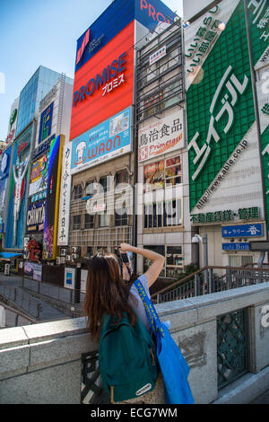 A girl is taking tourist pictures on a bridge in Dotonbori, Osaka Stock Photo