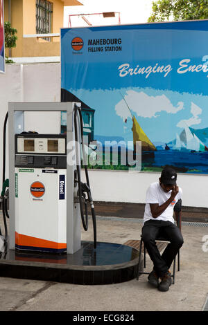 Mauritius, Mahebourg, town centre, Indian Oil petrol station, attendant using mobile phone on forecourt Stock Photo