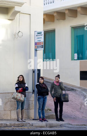 Local Maltese  Women waiting for a bus at the Mellieha bus stop in Malta Stock Photo