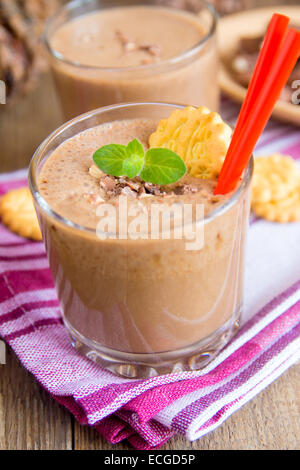 Milkshake (chocolate and banana smoothie) in glass with mint, cookies and nuts, homemade dairy breakfast or dessert vertical Stock Photo