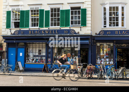 A cyclist passes Blackwell bookshop, a famous bookshop serving the town and University of Oxford located on Broad Street, Oxford Stock Photo