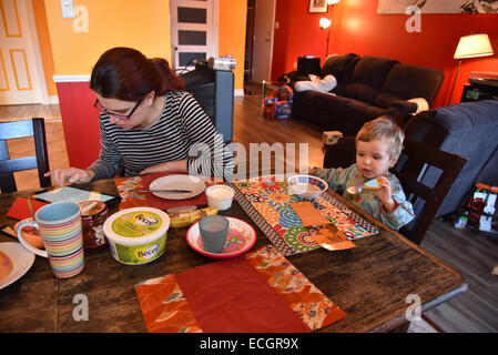 A mother ignoring her child reading an ipad at the breakfast table Stock Photo