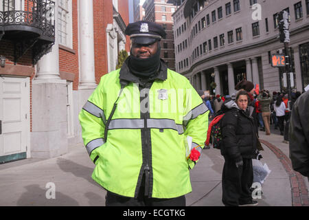 Boston, Massachusetts, USA. 13th December, 2014. A police officer watches as protesters walk through the streets for the Millions March rally in Boston, Massachusetts, USA.  The protest, like those in other cities throughout the United States on this day, is in response to recent grand jury verdicts not indicting police officers who  killed unarmed black men Michael Brown and Eric Garner, and to the longstanding problems of racism and police brutality. Credit:  Susan Pease/Alamy Live News Stock Photo