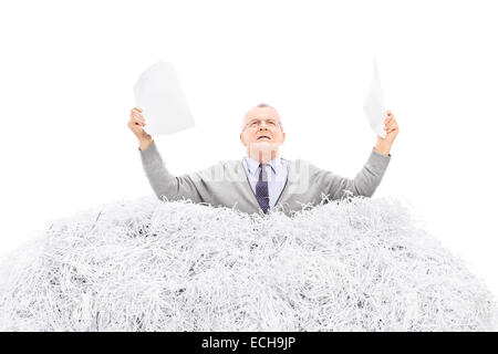Desperate senior holding a torn file in a pile of shredded paper isolated on white background Stock Photo