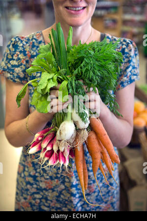 A bunch of radishes, carrots and spring onions at the Better Food Company organic supermaket in St. Werburgh's, Bristol UK Stock Photo