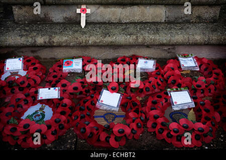 Poppy appeal wreaths laid in front of a war memorial, one wooden cross poppy rests on the memorial. Stock Photo