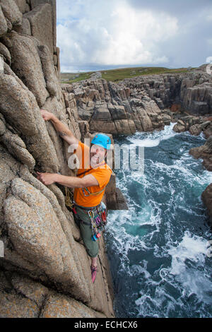 Iain Millar - a professional mountain guide - rock climbing up a sea stack near Gweedore, County Donegal, Ireland. Stock Photo