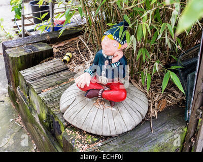 Garden gnome seated on a mushroom in a suburban garden, Twickenham, Greater London, England, UK Stock Photo