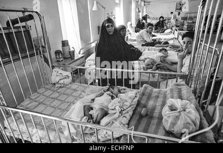Muslim mothers stay with the babies in the infant ward of  Saddam Hussein Children's Hospital in Baghdad.  The children are suffering from dysentery and dehydration because the water treatment plant was bombed during the Gulf War and there is no clean drinking water.  The hospital has no medicine because of UN Sanctions after the war. Stock Photo
