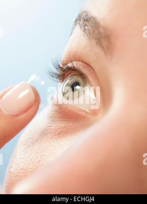 A close up at an angle of a female putting in a contact lens into her eye