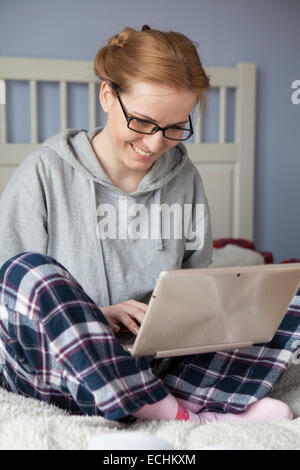 Young woman working on her laptop on the bed Stock Photo