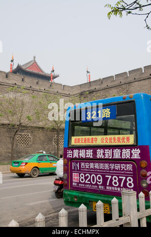 A multicoloured bus on the streets of Xi'an in China in front of the ancient walls of this Silk Road city Stock Photo