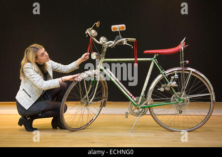 London, UK. 12 December 2014. A Christie's employee looks at the rhinestone encrusted bicycle customised by Bill Whitten for Elton John, used on stage during his 1974 American tour, estimate: GBP 4,000-6,000. Christie's unveils Memorabilia of Hollywood Icons & Music Legends from the 20/21 Pop Culture Sale ahead of a free public view from 13 to 16 December 2014, with the auction taking place on 16 December. The sale celebrates some of the great names of 20th century cinema and music legends, featuring costumes and film scripts, instruments and handwritten song lyrics. Stock Photo