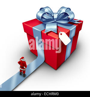 Santa clause gift seasonal winter symbol of giving as a jolly red costume man standing on a path in front of a giant present wrapped and decorated with a ribbon and bow on a white background. Stock Photo