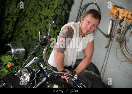 Portrait of young man leaning on motorbike Stock Photo