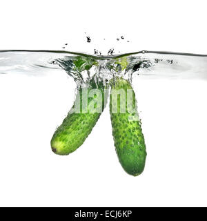 two green cucumbers dropped into water isolated on white Stock Photo