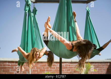 A woman takes bow pose while performing aerial yoga. Stock Photo
