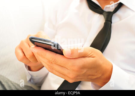 a relaxed young man using a smartphone Stock Photo