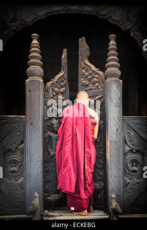 Myanmar (Burma), Mandalay Division, Innwa, Bagaya Kyaung, Burmese monk entering wooden door Stock Photo