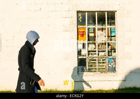 United Kingdom, Scotland, Argyll and Bute, Lochgilphead, urban texture, street scene of a young man in front of a white wall and a window of an old bazaar Stock Photo