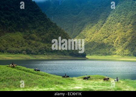 France, Reunion Island, Parc National de la Reunion (National Park of la Reunion), listed as World Heritage by UNESCO, Saint Benoit, Grand Etang, Equestrian tourism hiking, horizontal view of a group of riders ride around a pond Stock Photo