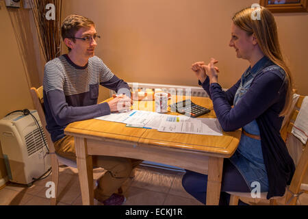 A young couple trying to work out their finances and how to pay mounting bills whilst sitting at a table. Stock Photo