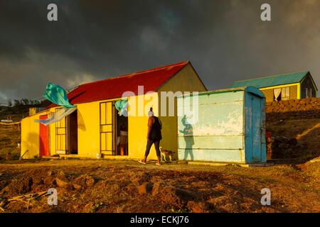 Mauritius, Rodrigues Island, Mourouk, creole woman in front of her hut accompanied by a small dog under a stormy sky at sunset Stock Photo