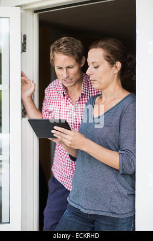 Couple using digital tablet at doorway Stock Photo
