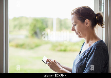 Side view of woman using digital tablet by window at home Stock Photo
