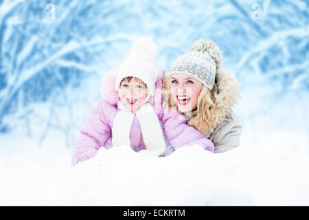 Happy parent mother and kid lying in snow outdoor Stock Photo