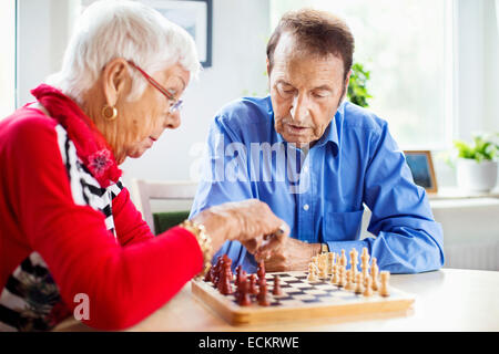 Senior couple playing chess at table in nursing home Stock Photo