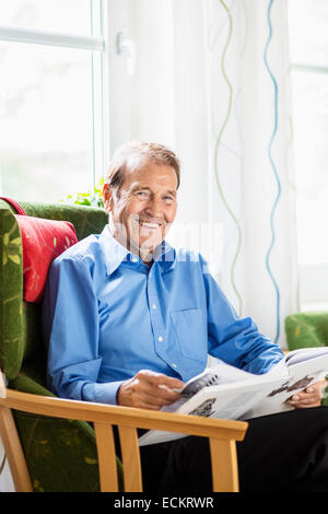 Portrait of happy senior man reading book at nursing home Stock Photo