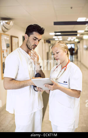 Doctors discussing over digital tablet in hospital corridor Stock Photo