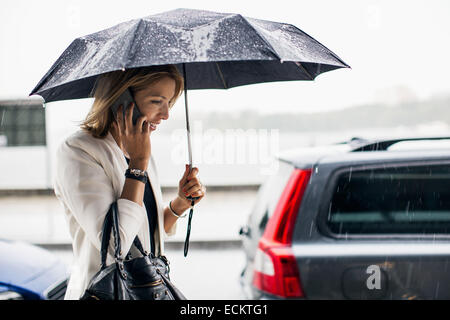 Businesswoman talking on smart phone during rainy season in city Stock Photo