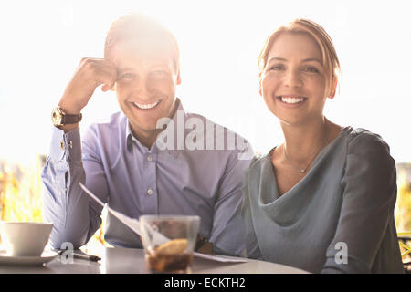 Portrait of happy business people at outdoor cafe against sky Stock Photo