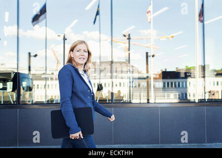 Confident businesswoman walking with file in front of office building Stock Photo