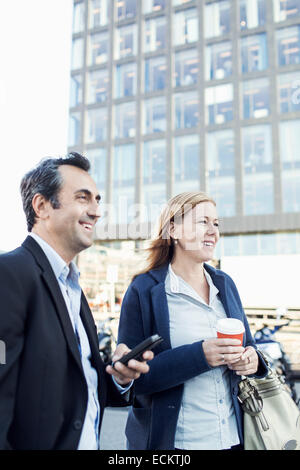 Happy businesspeople looking away while standing outside office building Stock Photo